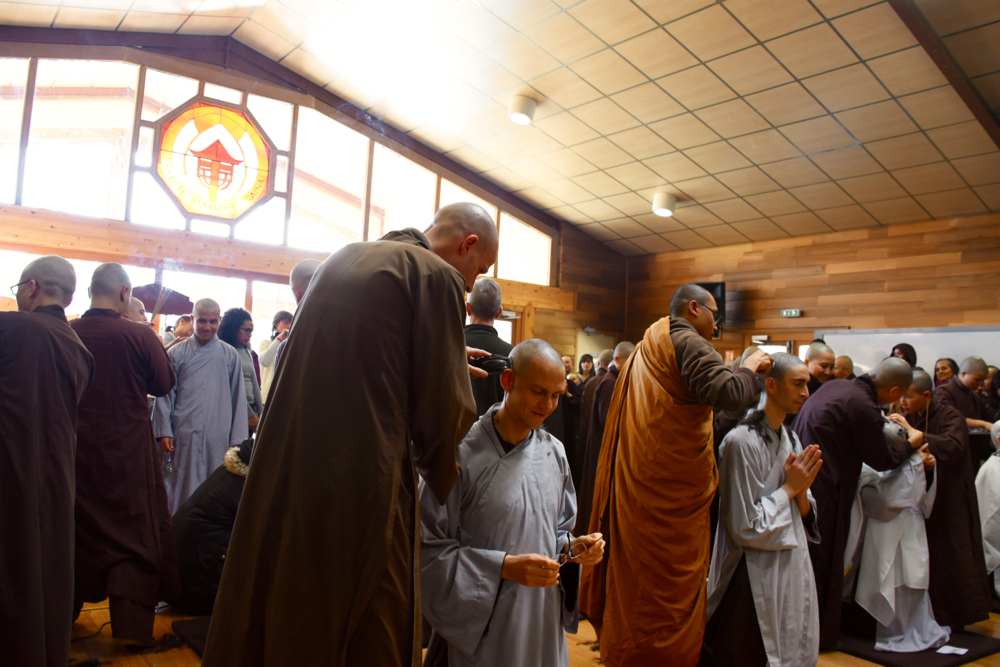 Toute la Sangha se tient les paumes de mains jointes en invoquant le nom d'Avalokiteshvara alors que les cheveux des nouveaux novices sont rasés. 