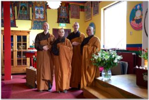 Quatre monastiques en robe marron et orange dans un temple tibétain