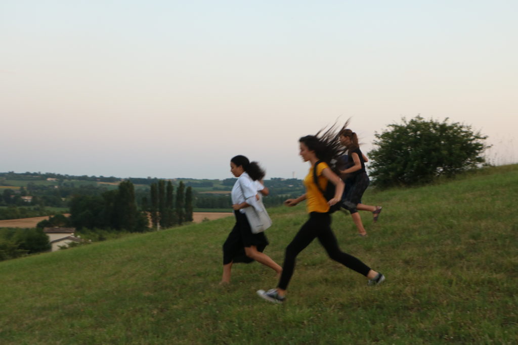 Trois adolescentes descendent la colline du Hameau Nouveau en courant.