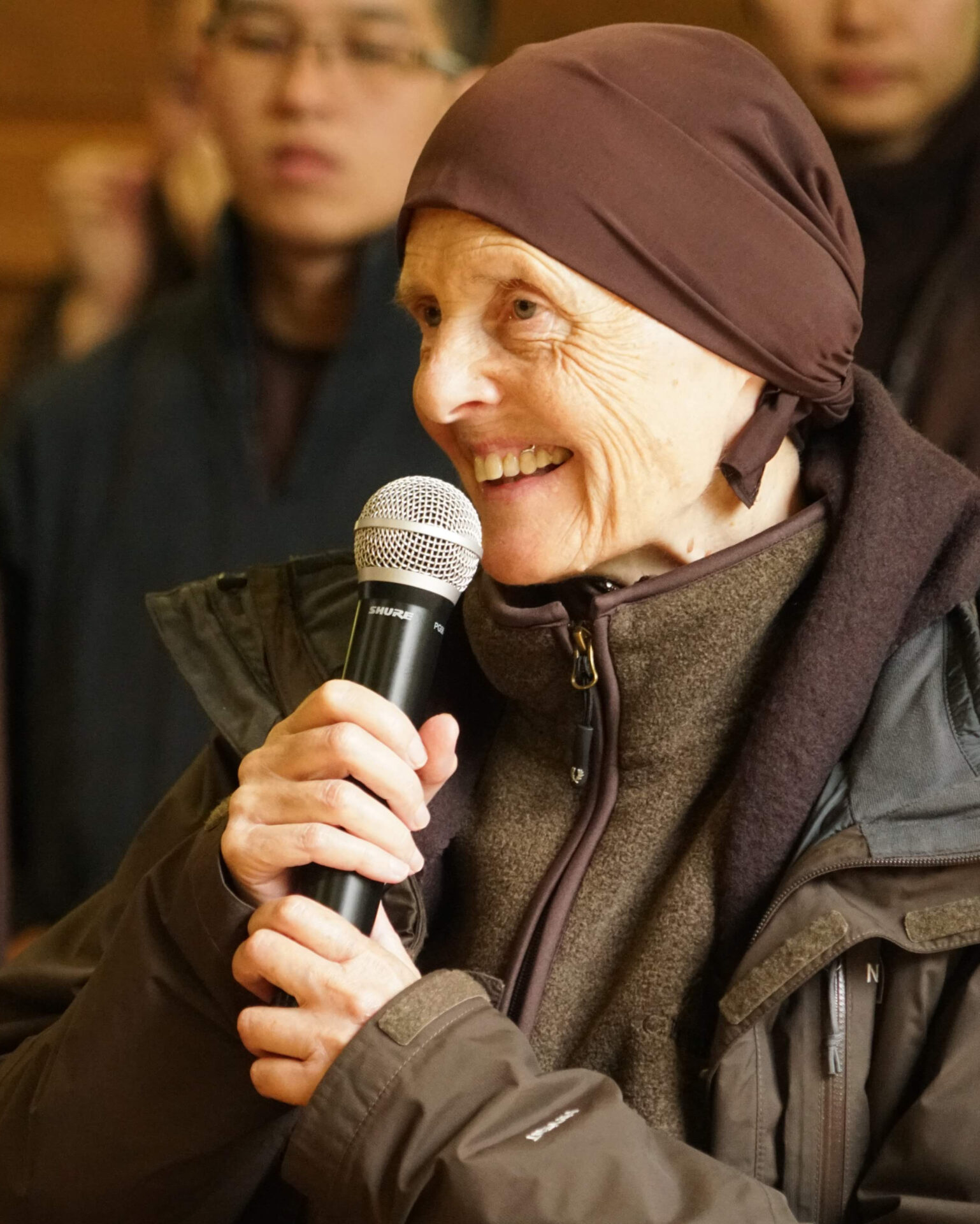 Sister Chan Duc is smiling and speaking into a microphone